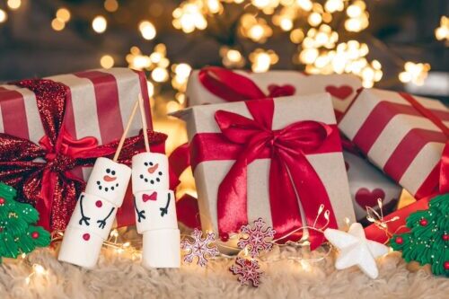 Christmas gift box on a background of Christmas tree, with marshmallow snowmen.