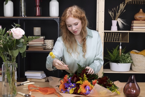 Woman in floral shop arranging a flower bouquet.